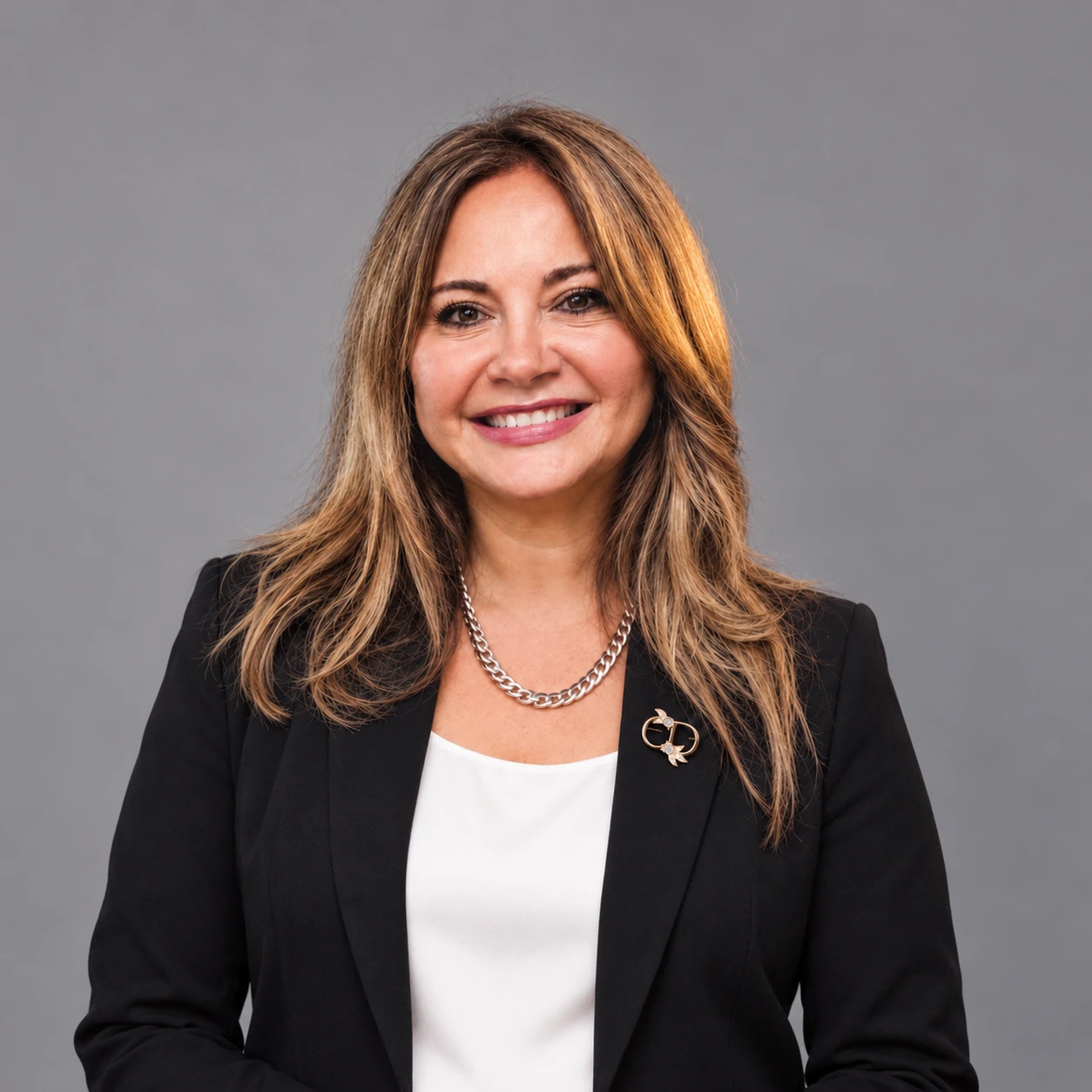 Portrait of Sil Coria wearing a dark jacket with a brooch