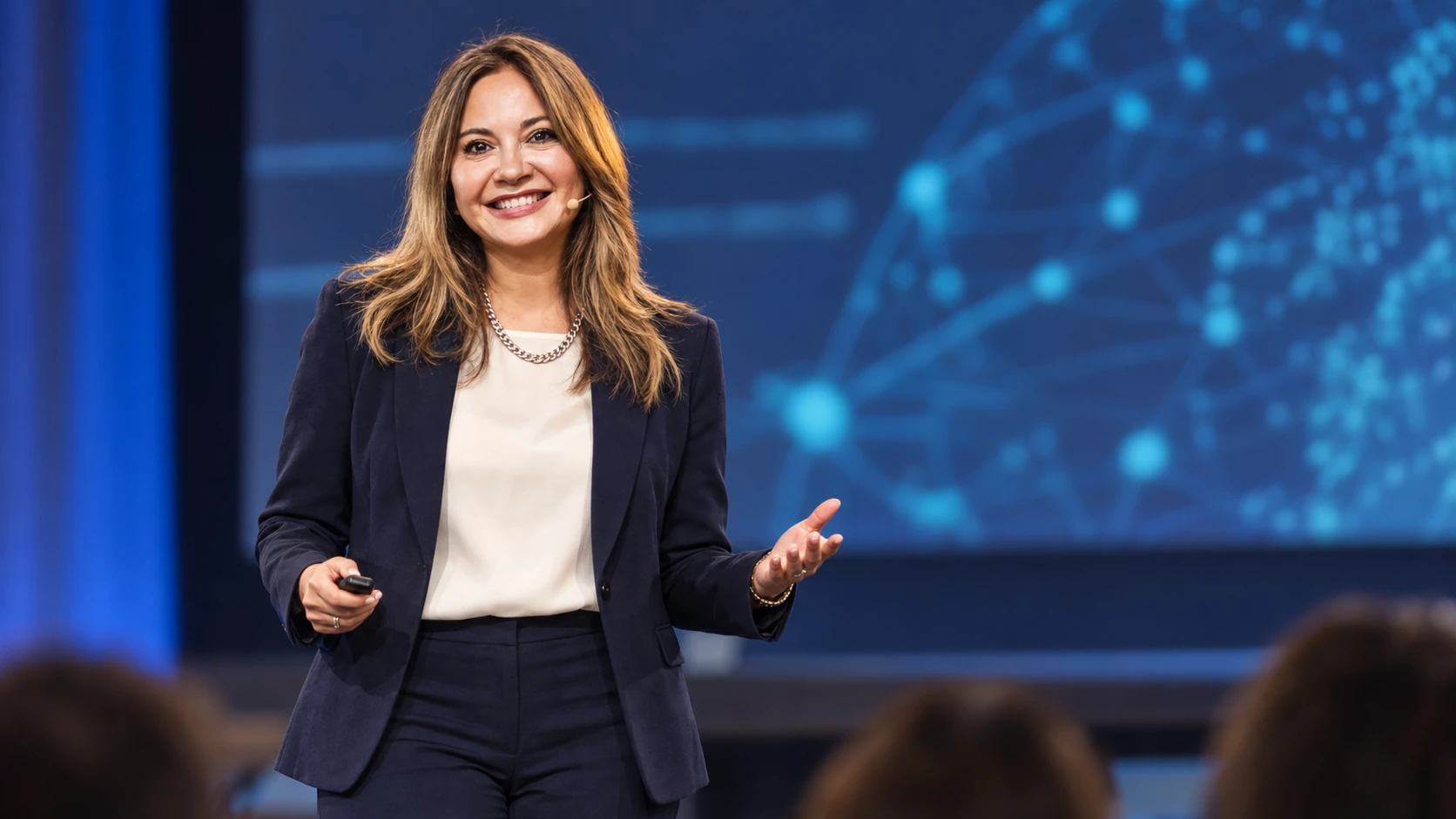 Sil Coria on stage with a microphone and presentation remote
